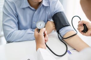 Doctor man is checking the blood pressure of the patient.