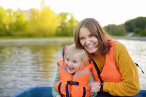 Mother with child in life vest on water